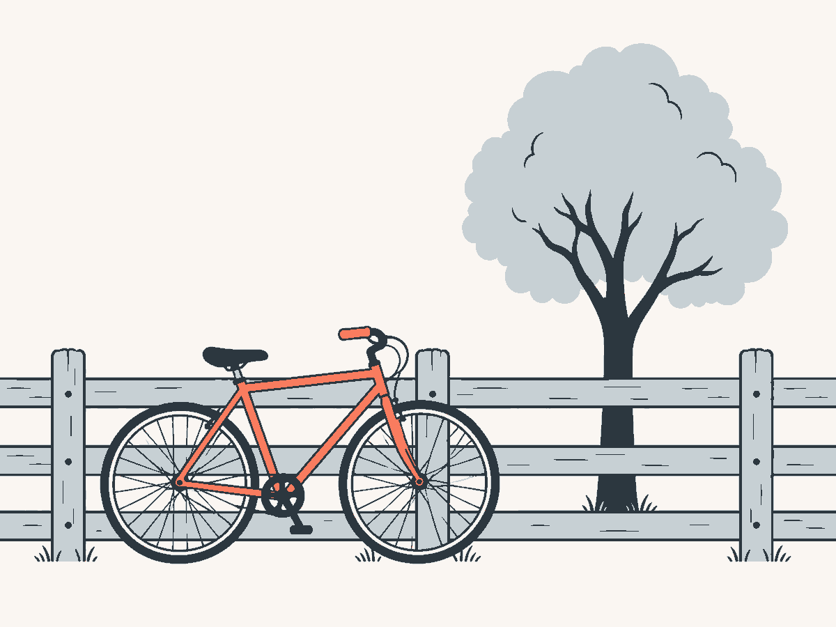Ein Fahrrad lehnt an einem Holzzaun, dahinter ein Baum.